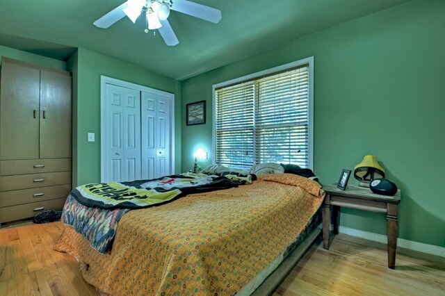 bedroom with light hardwood / wood-style floors, ceiling fan, and a closet