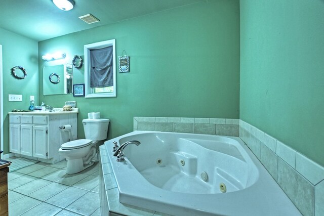 bathroom with tiled tub, vanity, toilet, and tile patterned flooring