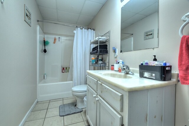 full bathroom featuring a paneled ceiling, tile patterned floors, shower / tub combo with curtain, vanity, and toilet