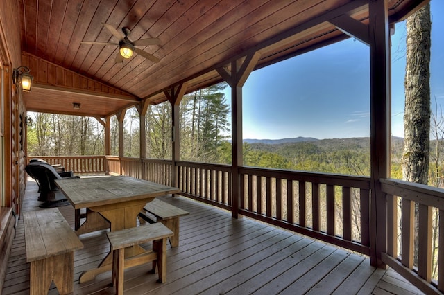 deck featuring a forest view, ceiling fan, and a mountain view