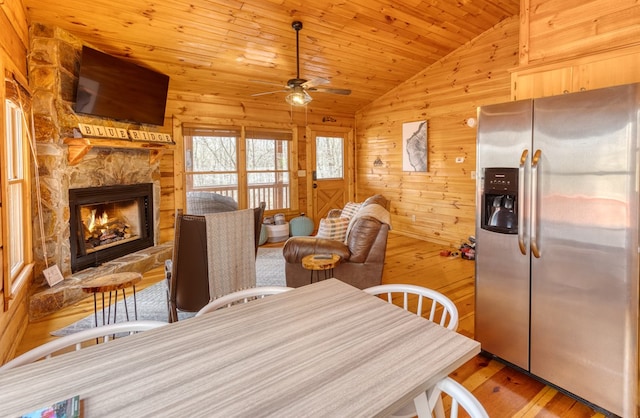 dining room featuring wooden walls, hardwood / wood-style flooring, wooden ceiling, a ceiling fan, and vaulted ceiling