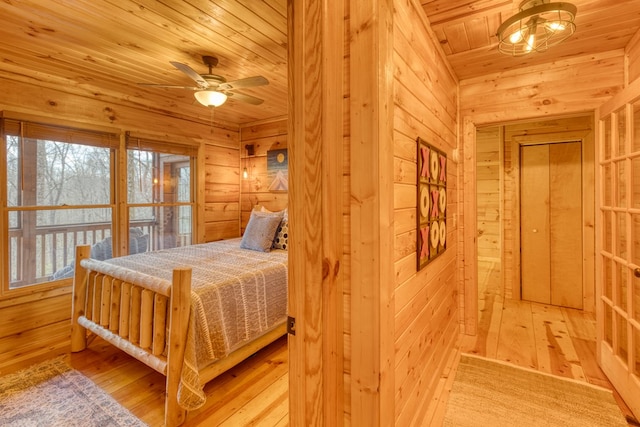 bedroom with light wood-style floors, wood ceiling, and wood walls