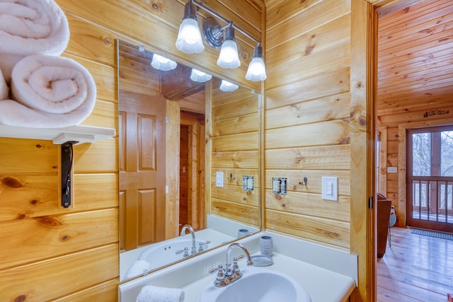 bathroom with wooden walls, a sink, and hardwood / wood-style floors