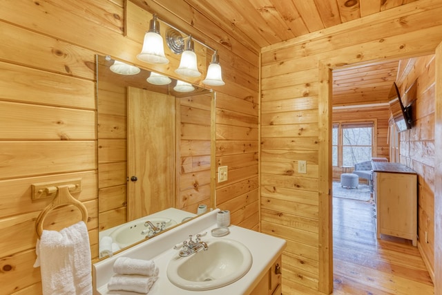bathroom featuring vanity, wood walls, wood finished floors, and wooden ceiling