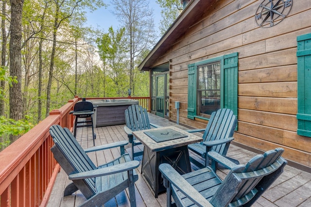 wooden deck with a hot tub and an outdoor fire pit