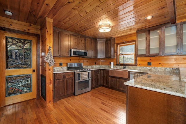 kitchen featuring light stone countertops, light wood-type flooring, stainless steel appliances, and wooden ceiling