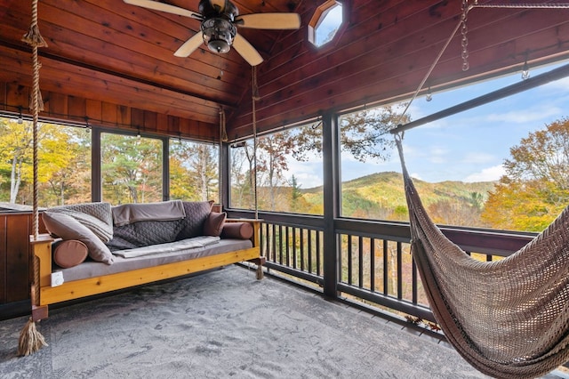 sunroom / solarium with a mountain view, ceiling fan, wooden ceiling, and vaulted ceiling