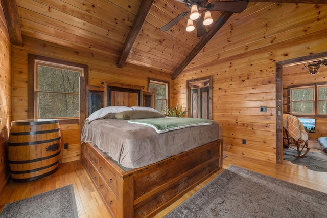 bedroom featuring multiple windows, wooden walls, and light wood-type flooring