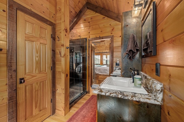 bathroom featuring hardwood / wood-style floors, lofted ceiling, wooden ceiling, sink, and wooden walls