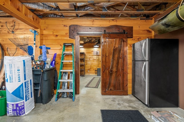 basement with wood walls and stainless steel fridge