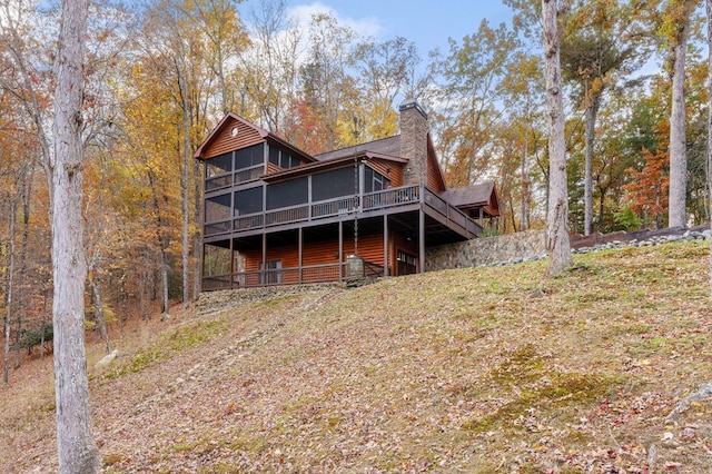 rear view of house featuring a wooden deck and a sunroom