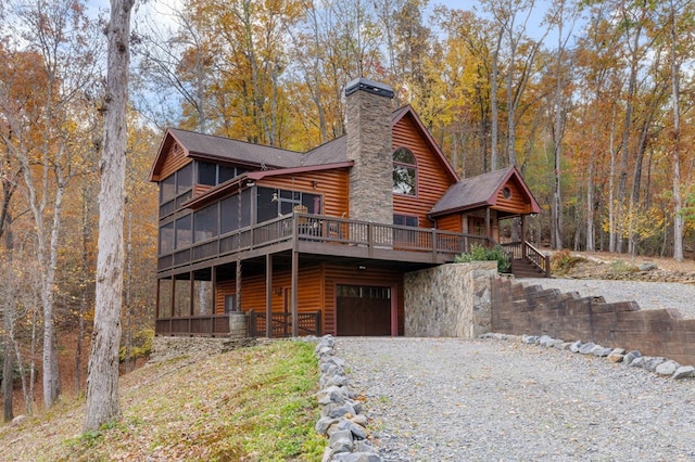 cabin with a sunroom, a garage, and a deck