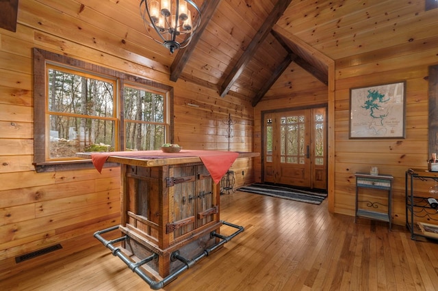 interior space featuring lofted ceiling with beams, wood-type flooring, and wooden walls