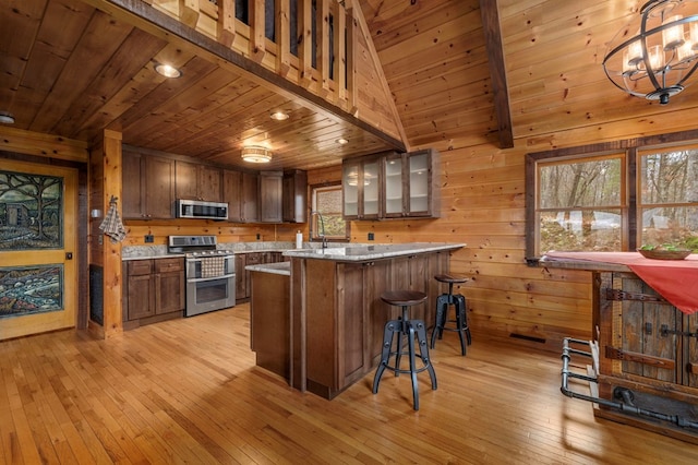 kitchen featuring appliances with stainless steel finishes, light hardwood / wood-style flooring, wooden walls, and wood ceiling