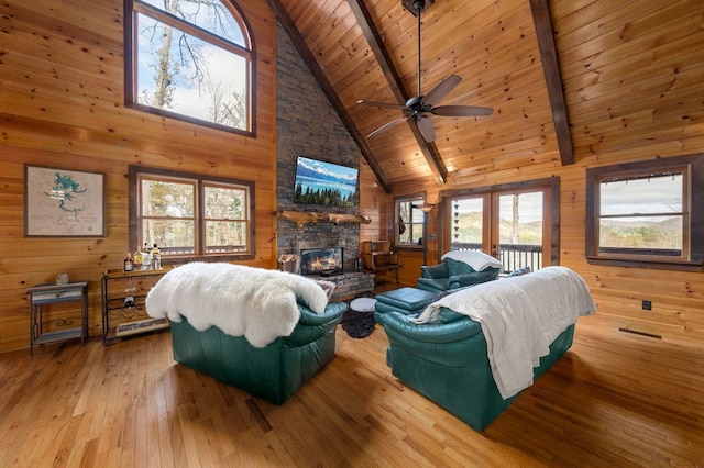 living room with beam ceiling, hardwood / wood-style flooring, high vaulted ceiling, and wood walls