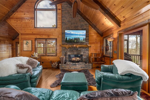 living room featuring a fireplace, wood walls, hardwood / wood-style floors, and high vaulted ceiling