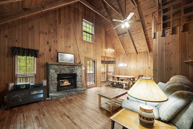 living area with wooden walls, a fireplace, a ceiling fan, wooden ceiling, and hardwood / wood-style flooring