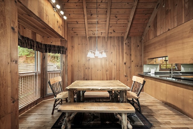 dining space featuring wood walls, hardwood / wood-style flooring, wooden ceiling, an inviting chandelier, and vaulted ceiling with beams