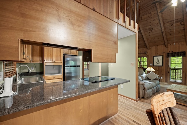 kitchen featuring a sink, lofted ceiling with beams, freestanding refrigerator, a peninsula, and light wood-style flooring