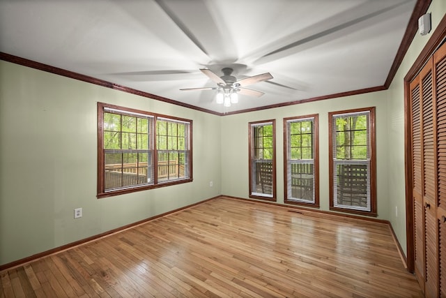 spare room featuring light wood-type flooring, ornamental molding, baseboards, and ceiling fan