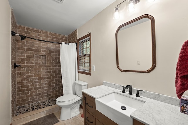 full bath with vanity, tile patterned flooring, a tile shower, and toilet