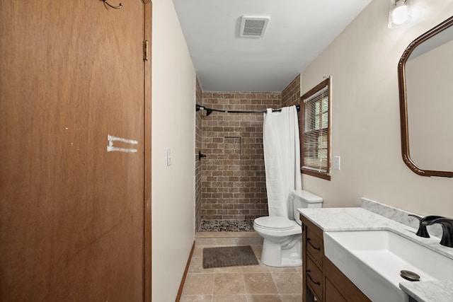 bathroom with visible vents, a tile shower, toilet, and vanity