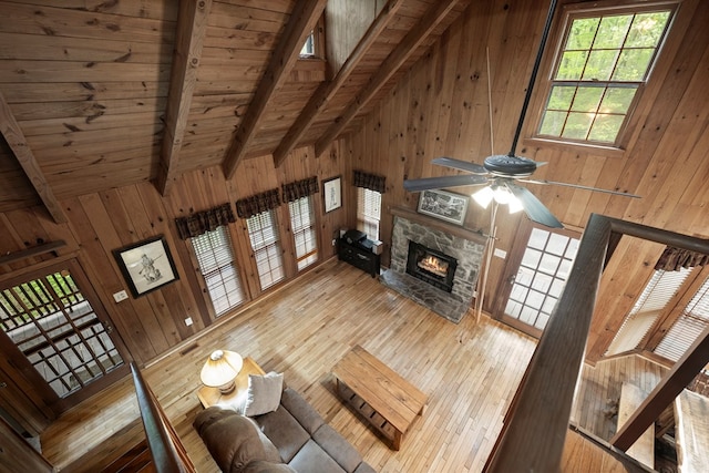 living room with vaulted ceiling with beams, wood ceiling, wooden walls, and hardwood / wood-style floors