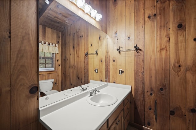 bathroom with vanity, wooden walls, and toilet