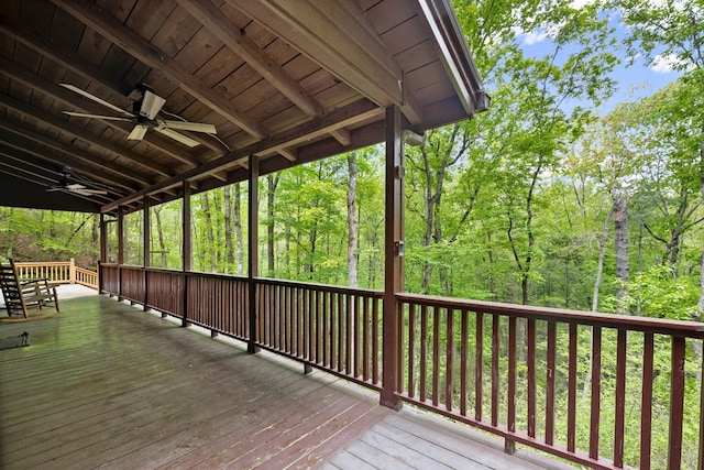 wooden deck with a ceiling fan and a forest view
