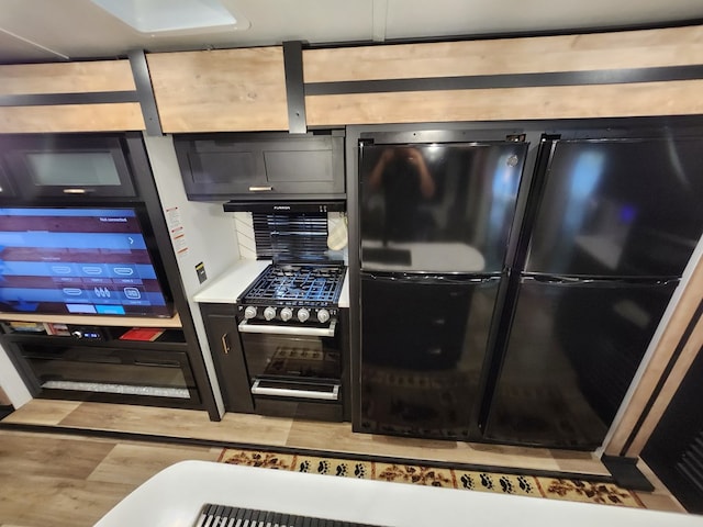 kitchen featuring light countertops, wood finished floors, freestanding refrigerator, and dark cabinets