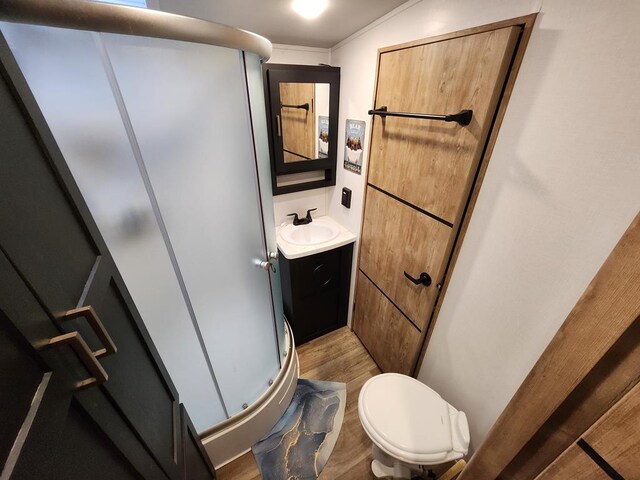 bathroom with crown molding, toilet, vanity, walk in shower, and wood-type flooring