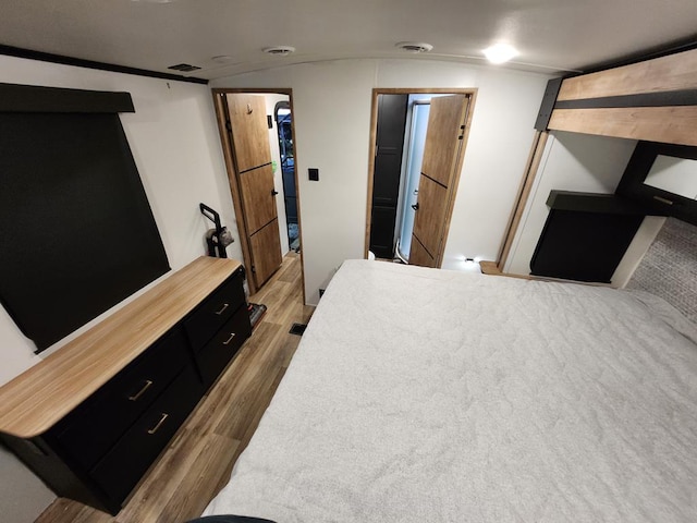 bedroom featuring lofted ceiling, visible vents, and wood finished floors