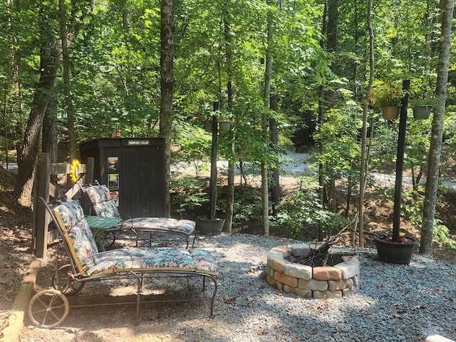 view of patio / terrace with an outdoor fire pit and a view of trees