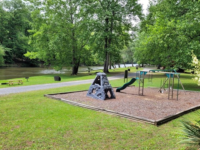 view of home's community featuring a playground, a lawn, and a water view