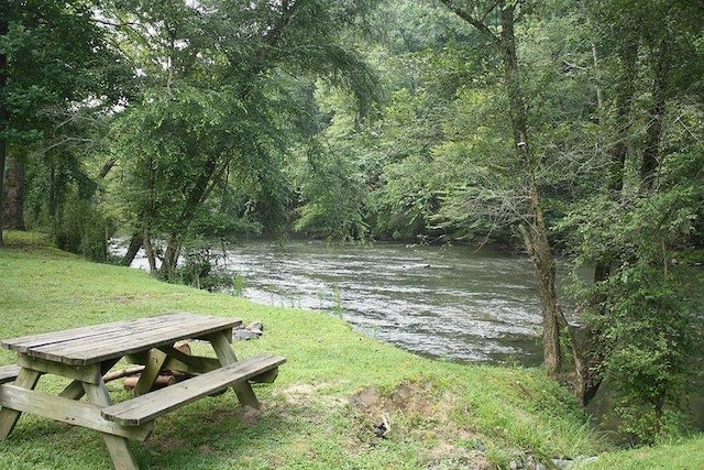 view of property's community featuring a yard, a water view, and a wooded view