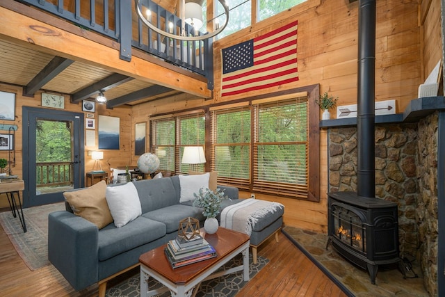 121 Farmstead Rd, Ellijay, GA 30540 - living room featuring a wood stove, a chandelier, wood walls, beamed ceiling, and hardwood / wood-style flooring