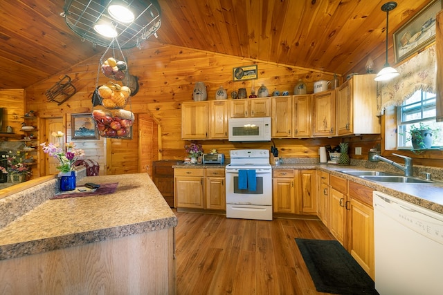 kitchen with wood walls, pendant lighting, white appliances, vaulted ceiling, and sink