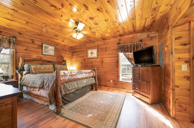 bedroom with ceiling fan, wooden walls, light hardwood / wood-style floors, and wood ceiling