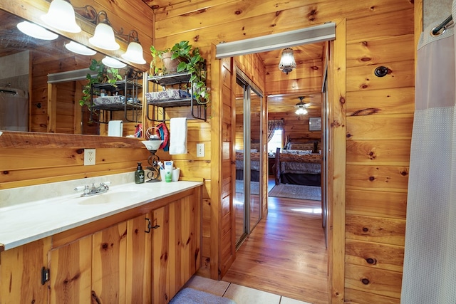 bathroom featuring vanity, hardwood / wood-style flooring, wooden walls, and ceiling fan