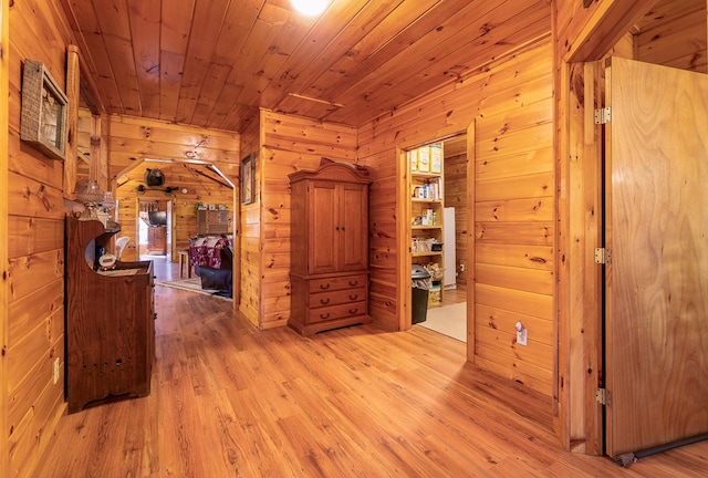 hallway featuring light hardwood / wood-style flooring, wood walls, and wooden ceiling