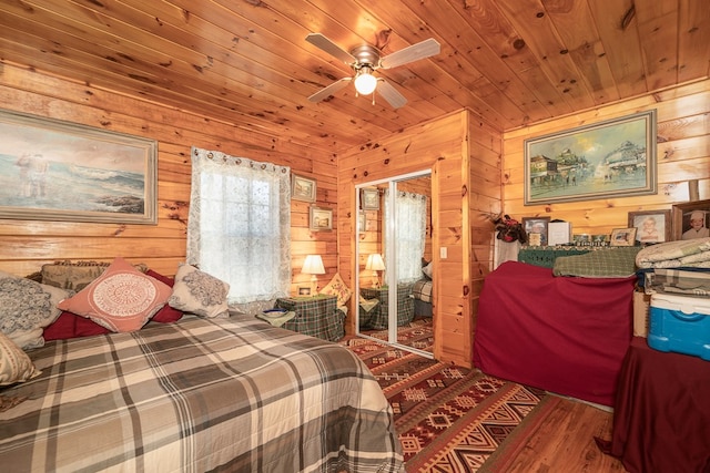 bedroom with ceiling fan, wood walls, wood-type flooring, and wooden ceiling