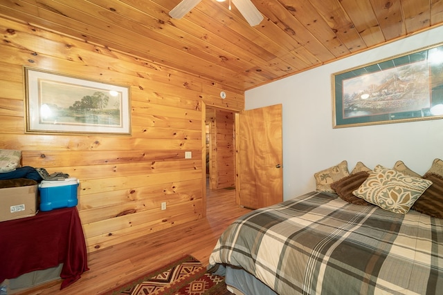 bedroom featuring hardwood / wood-style flooring, wooden walls, ceiling fan, and wood ceiling