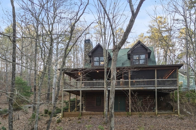 back of property with a sunroom and a chimney