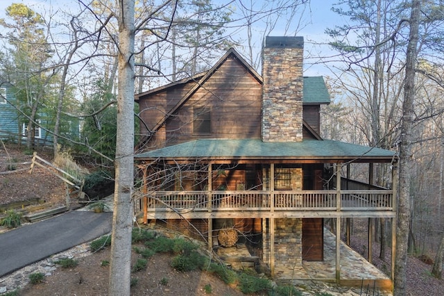 rear view of house featuring roof with shingles and a chimney