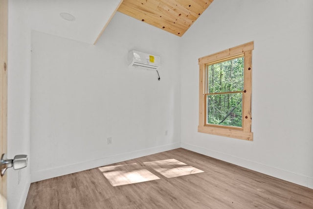 spare room featuring baseboards, lofted ceiling, wood finished floors, and a wall unit AC