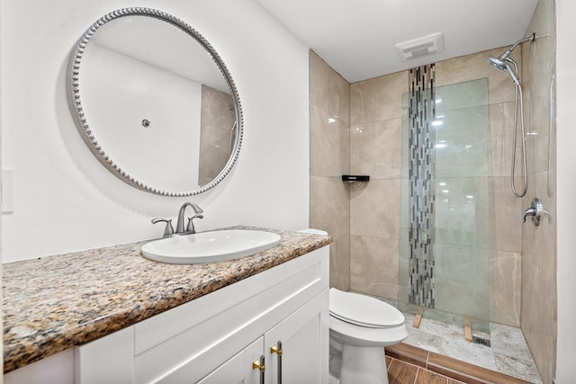 bathroom with vanity, toilet, a stall shower, and visible vents