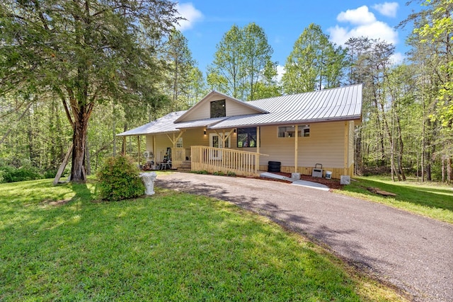 rear view of property with a standing seam roof, driveway, metal roof, covered porch, and a yard