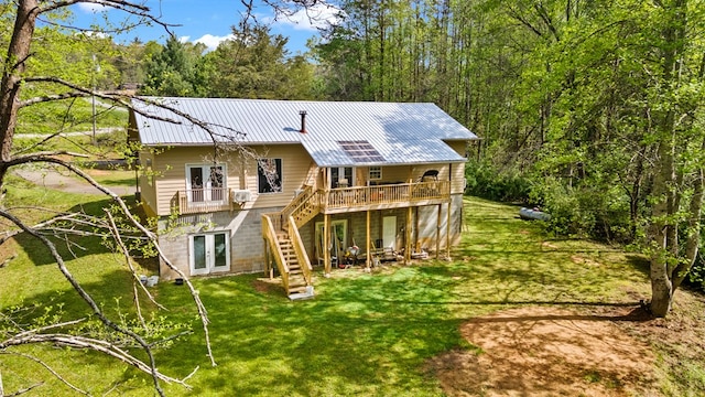 back of property with stairway, a lawn, french doors, metal roof, and a wooden deck