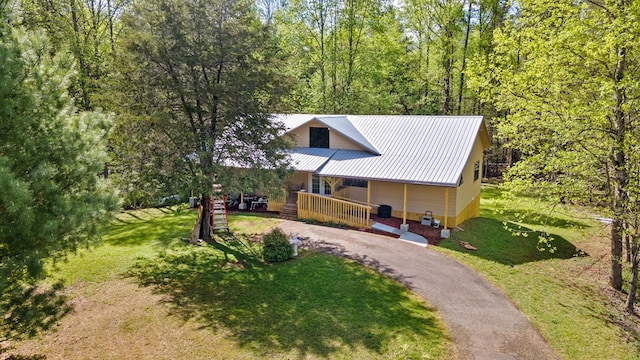 rustic home with driveway, a porch, metal roof, and a front yard