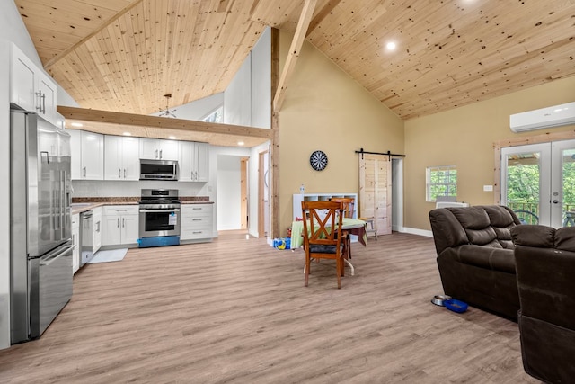 kitchen featuring high vaulted ceiling, a barn door, open floor plan, appliances with stainless steel finishes, and a wall unit AC